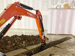 Using a digger to install a new drainage system in Harrow